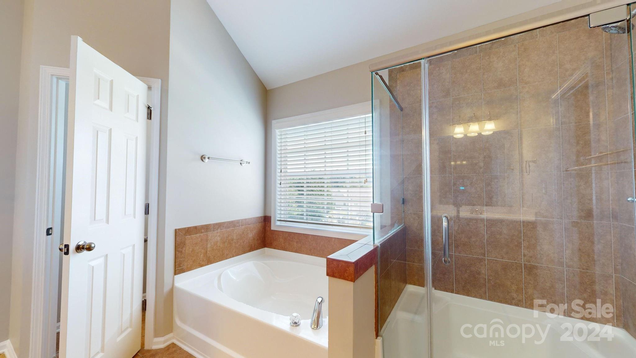 8386 Burgundy Ridge Drive Harrisburg, NC 28075 - Photo 31 of 44 a bathroom with a bathtub and a shower