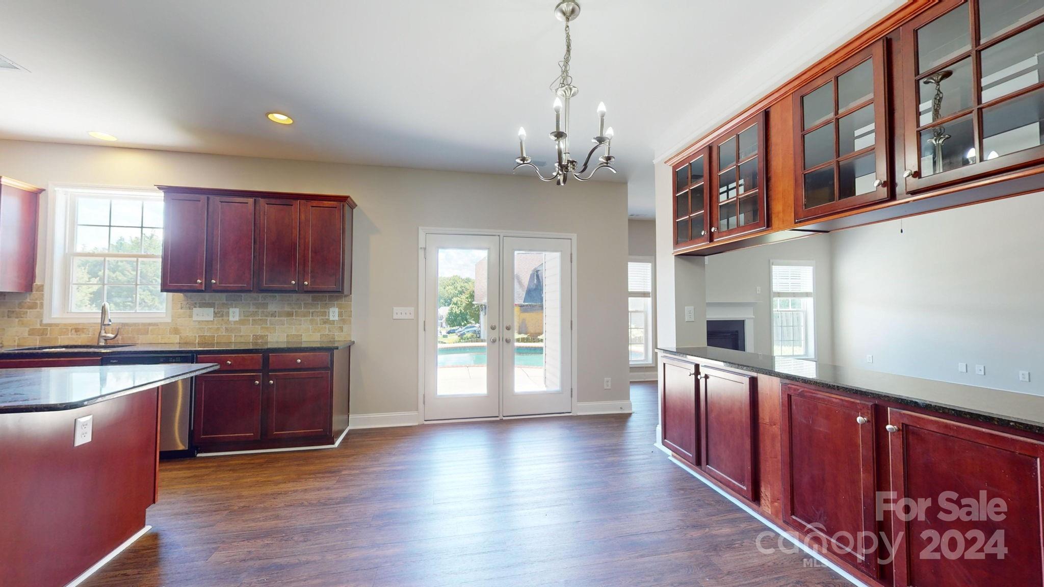 8386 Burgundy Ridge Drive Harrisburg, NC 28075 - Photo 9 of 44 a large kitchen with stainless steel appliances granite countertop a dishwasher and wooden cabinets with wooden floor