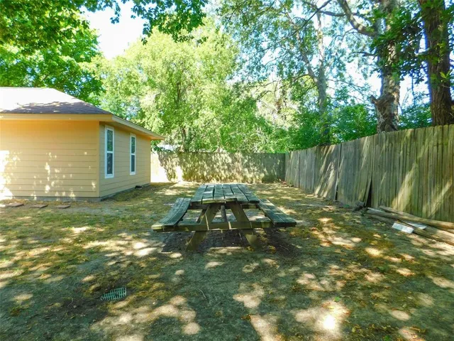 a backyard of a house with table and chairs under an umbrella