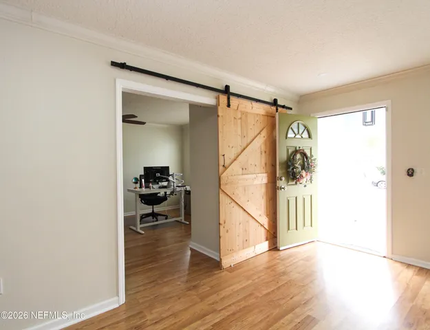 a view of a hallway with wooden floor and a livingroom