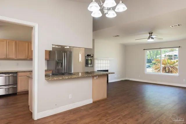 a kitchen with stainless steel appliances granite countertop a sink a stove and a wooden floors