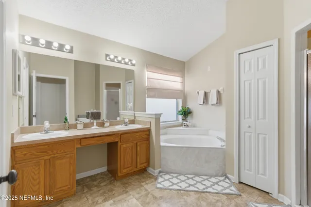 a bathroom with a double vanity sink mirror and bathtub