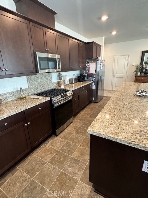 5233 Saloon Street Hemet, CA 92545 - Photo 14 of 28 a kitchen with stainless steel appliances granite countertop wooden cabinets a stove a sink and a oven