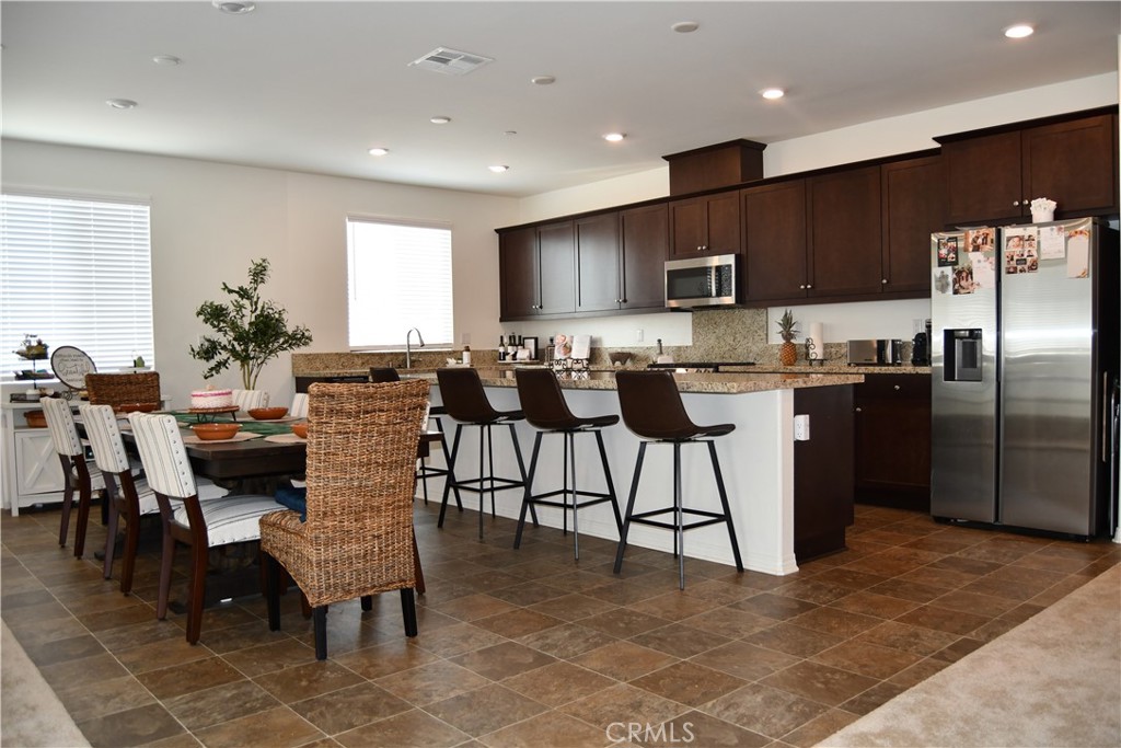 5233 Saloon Street Hemet, CA 92545 - Photo 4 of 28 a kitchen with stainless steel appliances kitchen island granite countertop a table chairs sink and cabinets