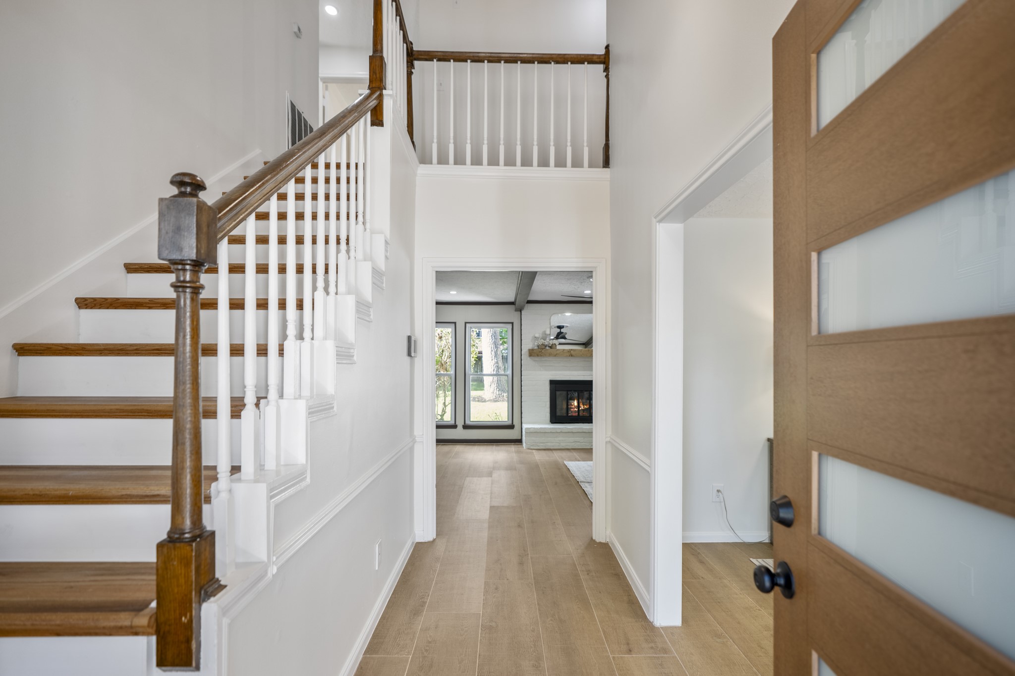 6303 Larkmount Drive Spring, TX 77389 - Photo 4 of 50 Stepping through the new front door, the home immediately opens up with fresh finishes and a bright, updated feel. Warm oak stairs, new wood-look tile flooring, fresh paint, and modern lighting come together in the foyer, while the staircase creates a natural transition between the downstairs living spaces and the rooms waiting upstairs.