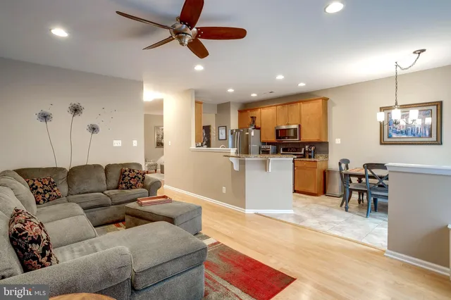 a living room with furniture kitchen view and a wooden floor