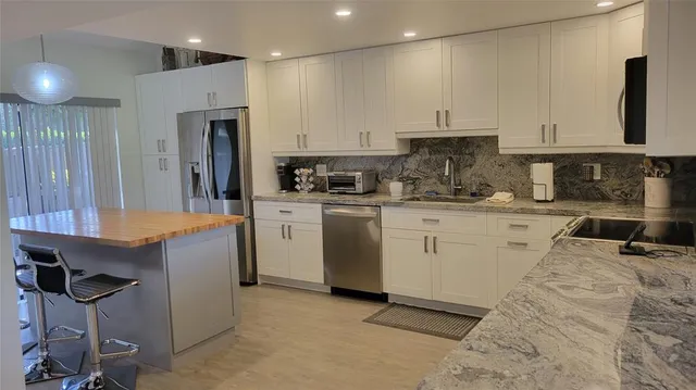 a kitchen that has a lot of white cabinets and stainless steel appliances