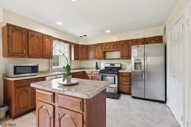 a kitchen with kitchen island granite countertop stainless steel appliances a stove a sink a refrigerator cabinets and a center island