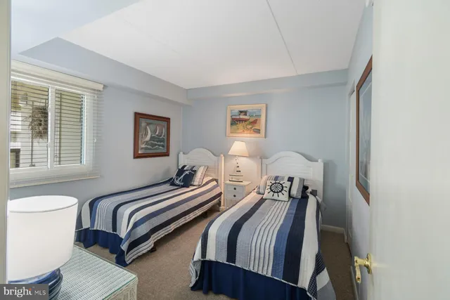 a bedroom with two beds lamp and a window