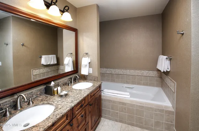 a bathroom with a granite countertop bathtub sink and mirror
