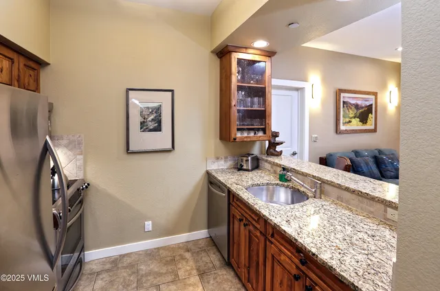 a kitchen with granite countertop a sink stove and refrigerator
