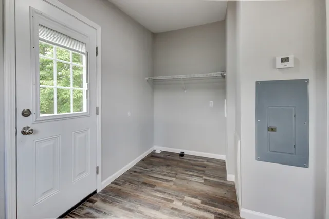 a view of an empty room with wooden floor and a window