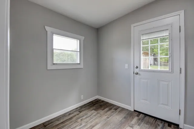 a view of an empty room with wooden floor and a window