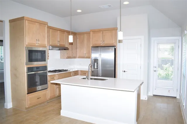 a kitchen with stainless steel appliances a sink a microwave a stove and white cabinets