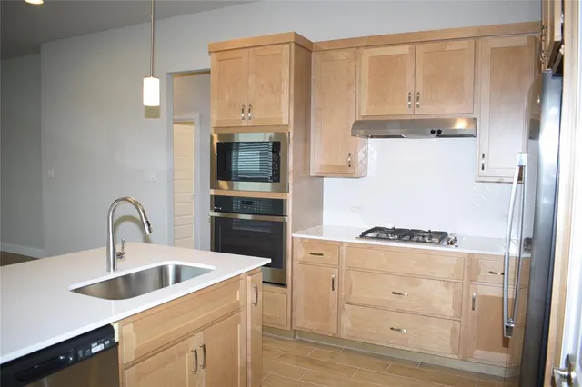 a kitchen with stainless steel appliances granite countertop a refrigerator a stove and white cabinets with wooden floor