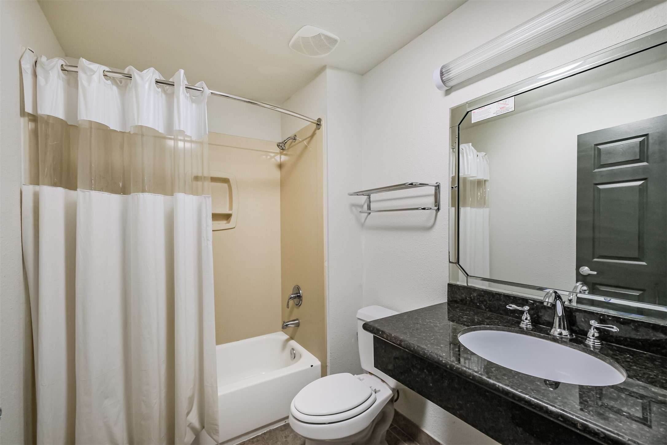 1025 Swanson Street, Unit 211 Houston, TX 77030 - Photo 15 of 18 a bathroom with a granite countertop sink toilet a mirror a bathtub and shower