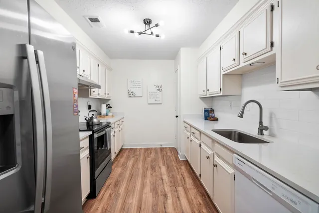a kitchen with white cabinets stainless steel appliances and sink