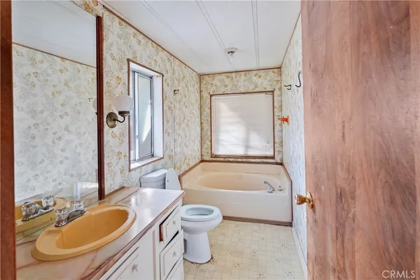 a bathroom with a granite countertop tub sink toilet and mirror