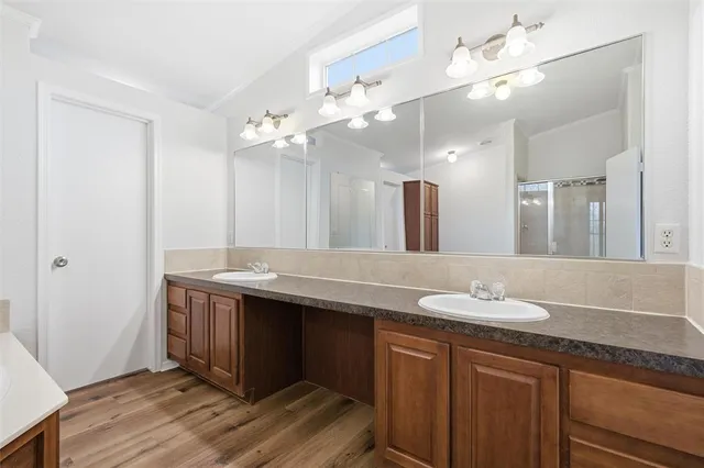 an empty room with wooden floor chandelier fan and windows