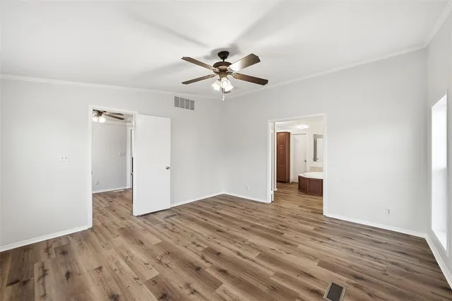 a view of an empty room with a window and wooden floor