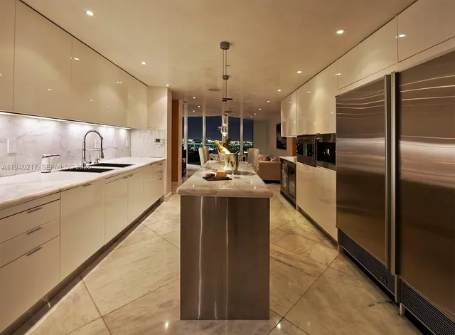 a kitchen with stainless steel appliances kitchen island granite countertop a sink and a refrigerator