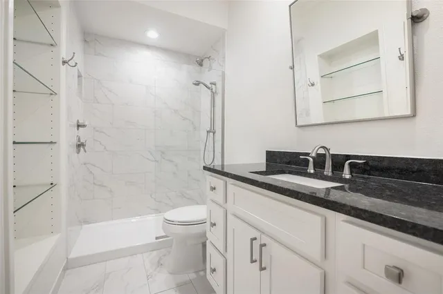 a bathroom with a granite countertop sink a toilet and shower
