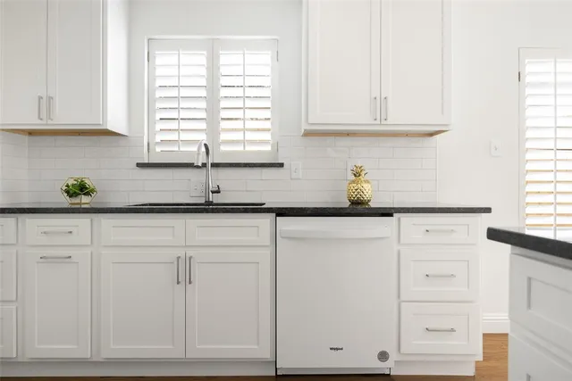 a kitchen with white cabinets and a window