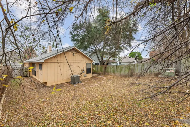 a backyard of a house with large trees and table and chairs