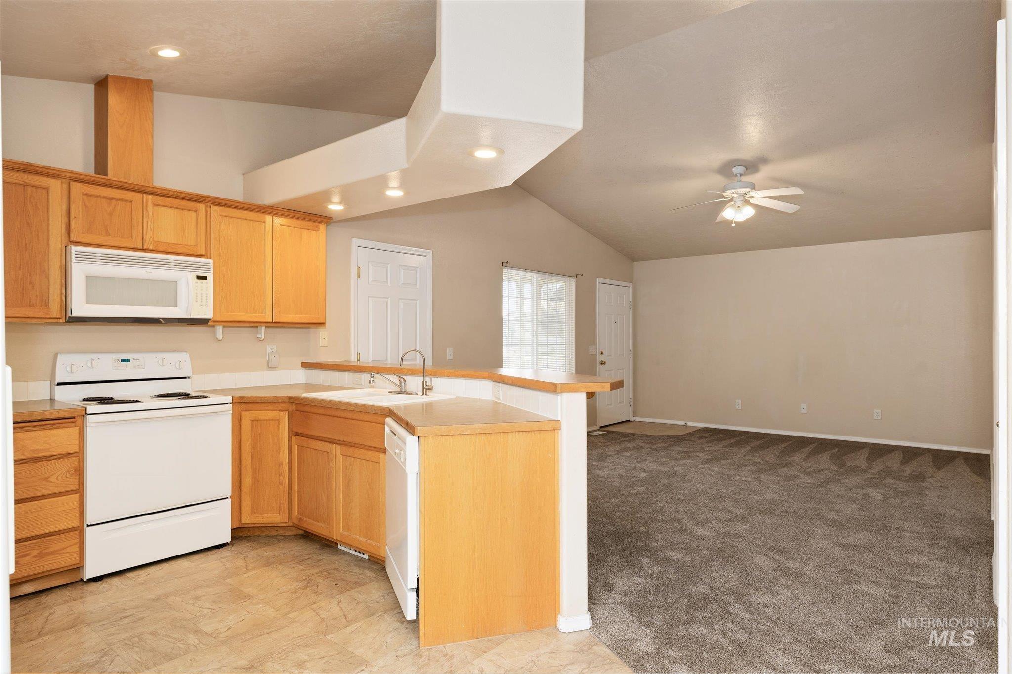 17925 Monarch Way Nampa, ID 83687 - Photo 29 of 29 Kitchen featuring white appliances, a peninsula, lofted ceiling, open floor plan, and light colored carpet