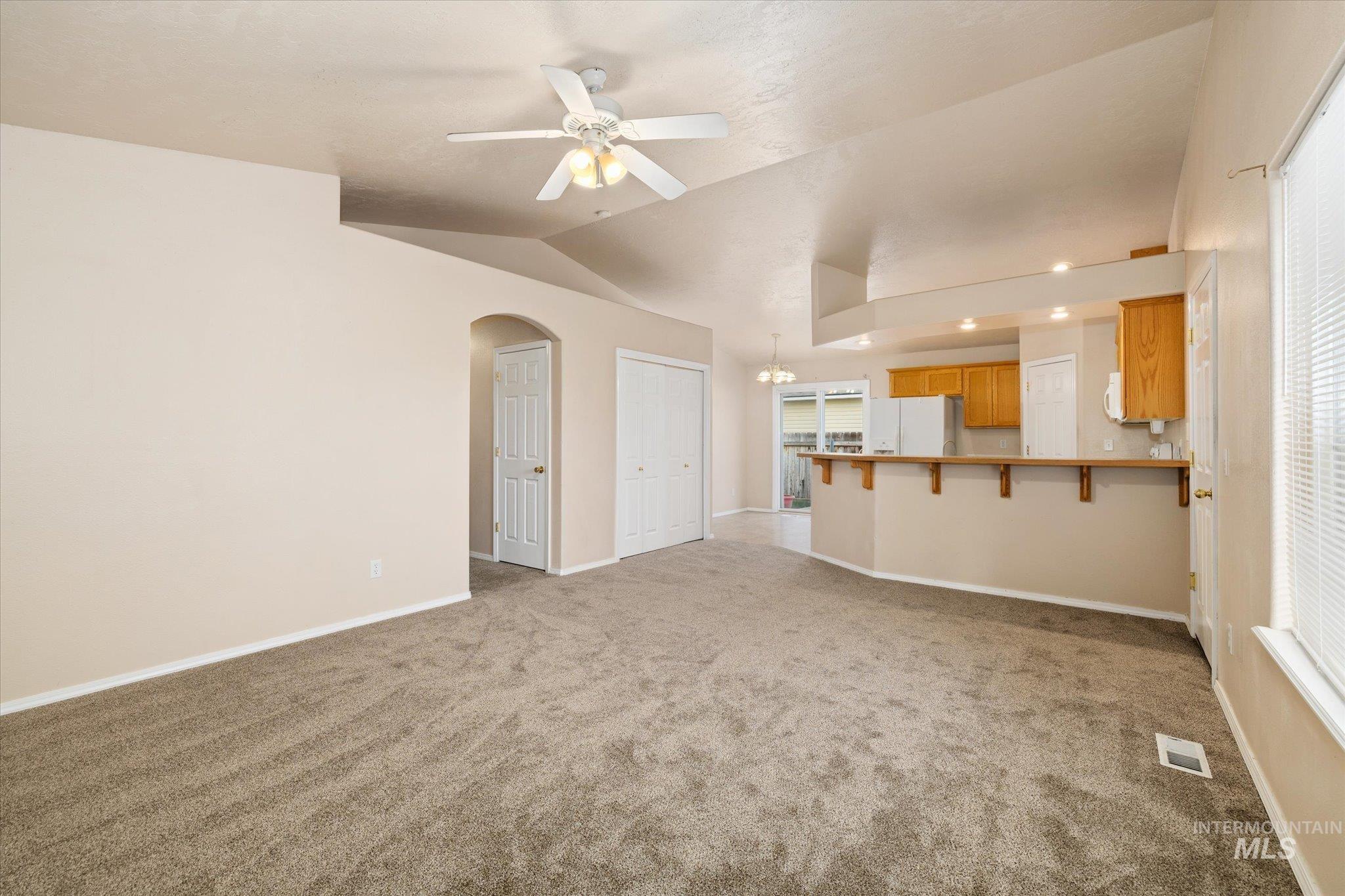 17925 Monarch Way Nampa, ID 83687 - Photo 6 of 29 Unfurnished living room featuring vaulted ceiling, a ceiling fan, arched walkways, light colored carpet, and a chandelier