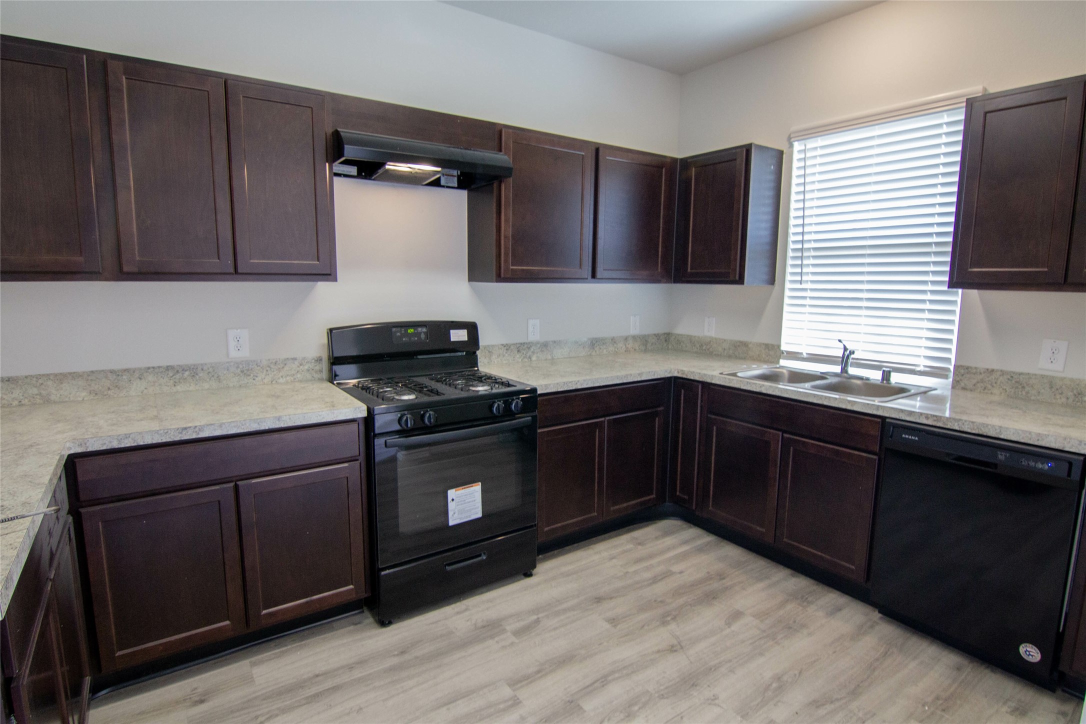 18638 Bell Ravine Drive Katy, TX 77449 - Photo 8 of 19 a kitchen with granite countertop wood cabinets and black appliances