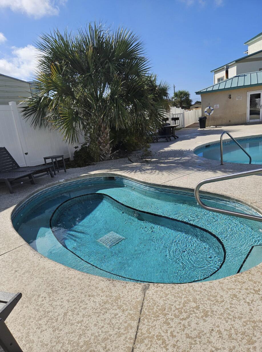 17878 Front Beach Road, Unit A1 Panama City Beach, FL 32413 - Photo 36 of 42 a view of a swimming pool with a chair and palm trees