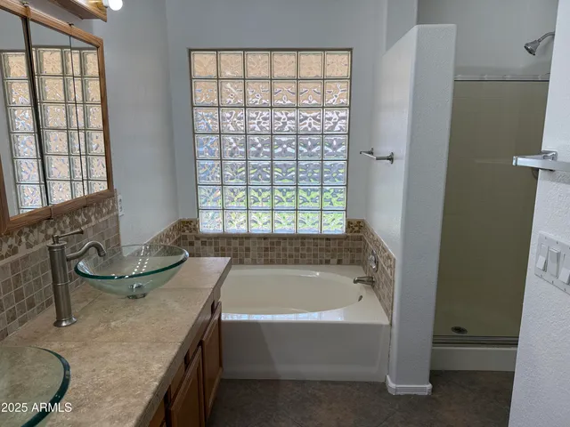 a bathroom with a granite countertop tub sink and mirror