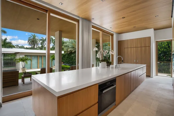 a large kitchen with kitchen island a large window in it