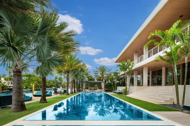 a view of a swimming pool with a lawn chairs and a big yard