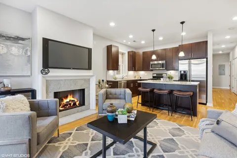 a living room with stainless steel appliances furniture a fireplace and a flat screen tv