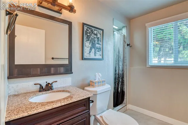 a bathroom with a granite countertop sink vanity mirror and a toilet