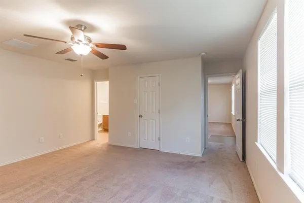 a view of an empty room and window with a ceiling fan