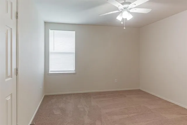 an empty room with a window and a fan