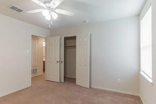 an empty room with chandelier fan and windows