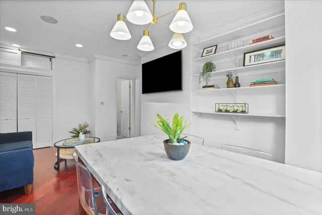 a kitchen with stainless steel appliances granite countertop a stove a sink a microwave a dining table and chairs with wooden floor