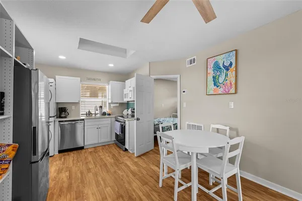 a kitchen with stainless steel appliances granite countertop a refrigerator a stove top oven a sink dishwasher and a dining table with wooden floor