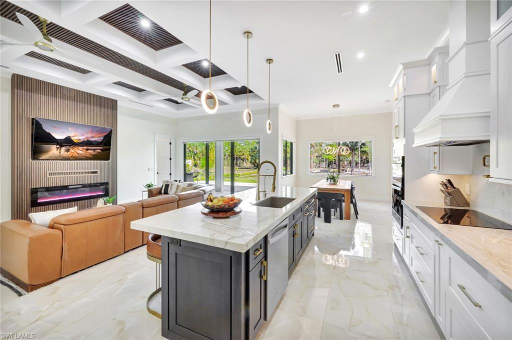 2546 4th Street Northwest Naples, FL 34120 - Photo 44 of 44 Kitchen featuring white cabinets, light stone countertops, coffered ceiling, open floor plan, and pendant lighting