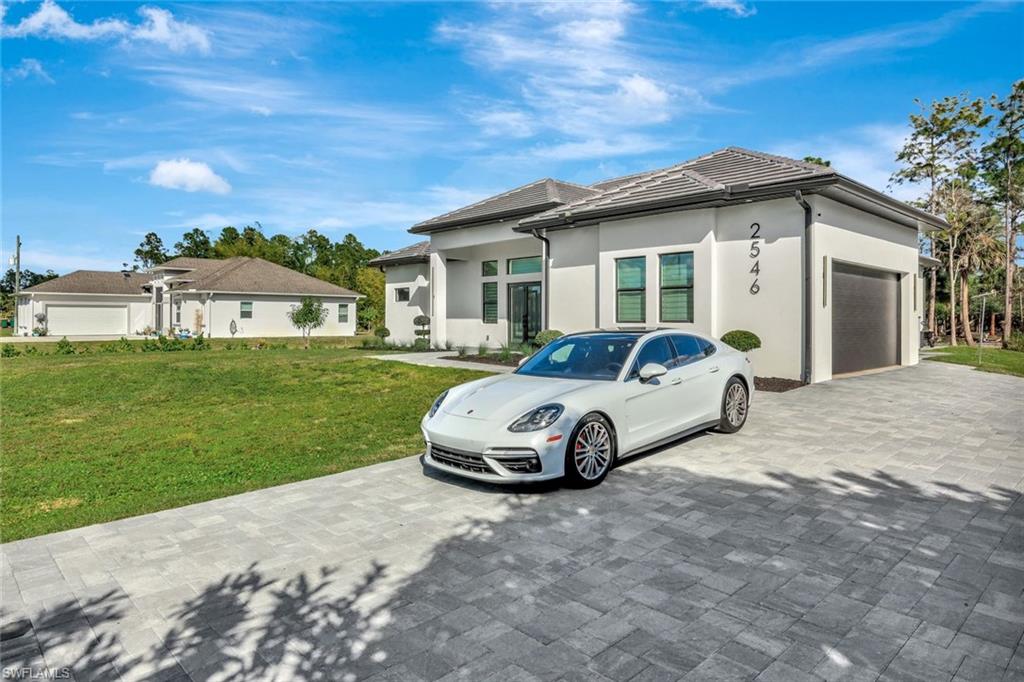 2546 4th Street Northwest Naples, FL 34120 - Photo 41 of 44 View of front of house with a garage, a front yard, stucco siding, and decorative driveway