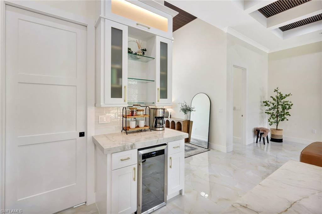 2546 4th Street Northwest Naples, FL 34120 - Photo 9 of 44 Bar featuring white cabinets, light stone countertops, wine cooler, glass insert cabinets, and light marble finish floors