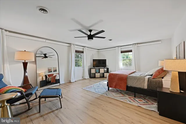 a living room with blue couches and a potted plant with wooden floor