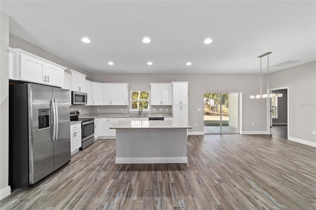 13359 Southwest 80th Street Dunnellon, FL 34432 - Photo 27 of 64 a kitchen with stainless steel appliances a refrigerator a sink dishwasher a stove and white cabinets with wooden floor