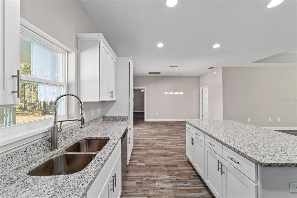 13359 Southwest 80th Street Dunnellon, FL 34432 - Photo 29 of 64 a kitchen with granite countertop a sink and a stove with wooden floor