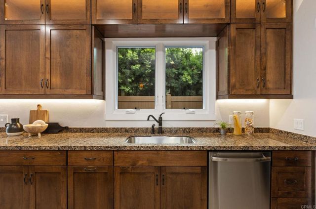 a kitchen with granite countertop a sink window and cabinets