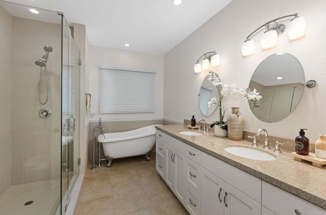 a bathroom with a double vanity sink mirror and bathtub